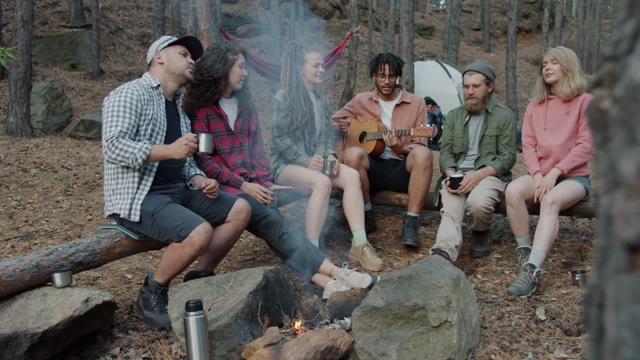 Friends Singing Around Campfire in Forest