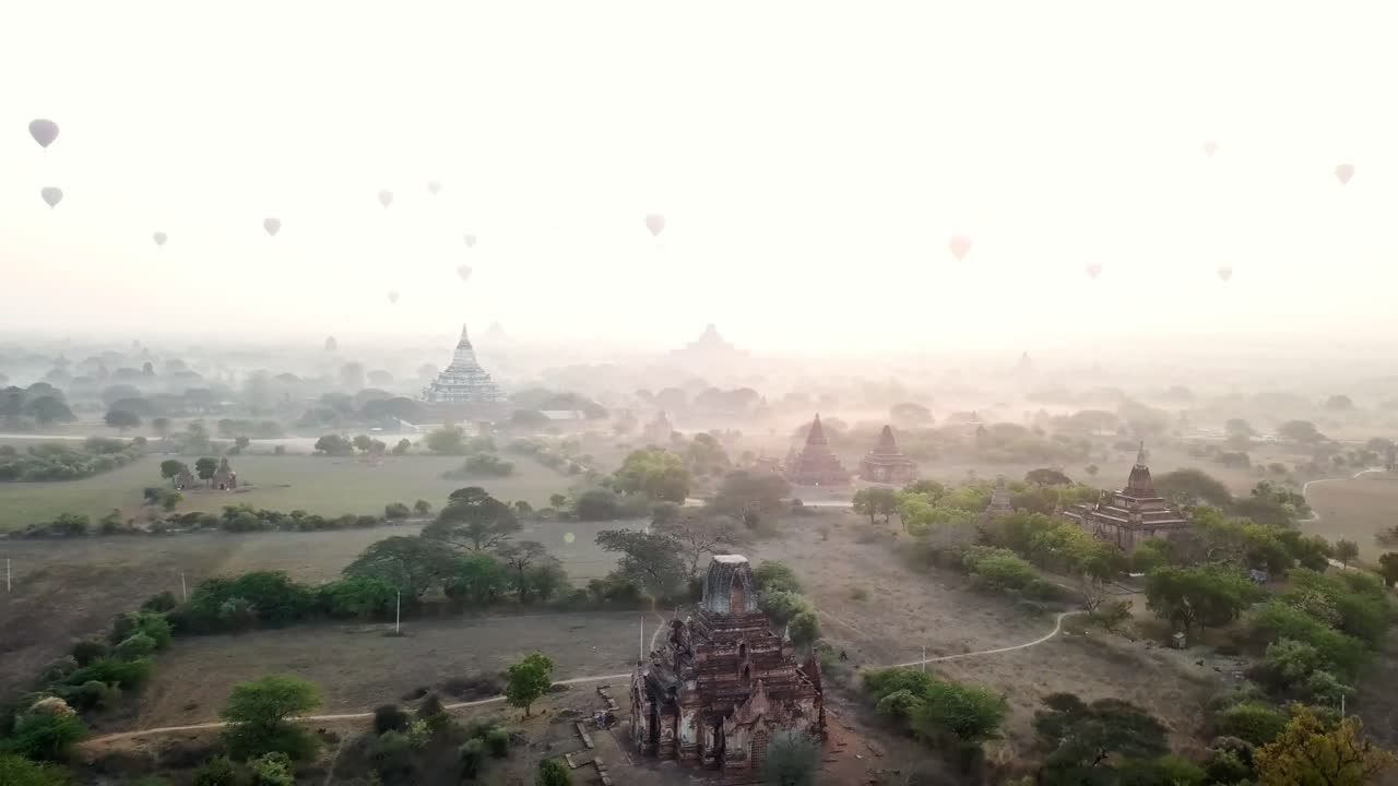 Hot air balloons soaring gracefully over the ancient temples of Bagan in Myanmar at sunrise, creating a breathtaking and magical atmosphere filled with wonder and tranquility, drone shot