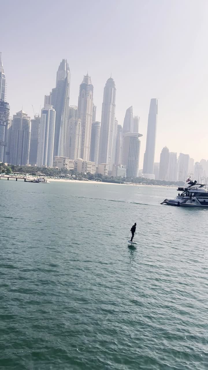 Person Riding an eFoil Board with Dubai City Skyline in Background