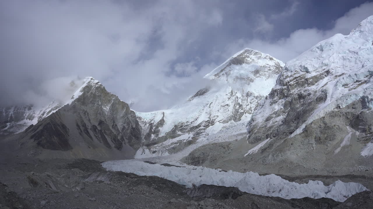 Snow and ice-covered mountain ranges at Gorakshep, 5000m altitude on the Everest Base Camp trek, with clouds gently covering the peaks, offering a stunning and shining view landscape