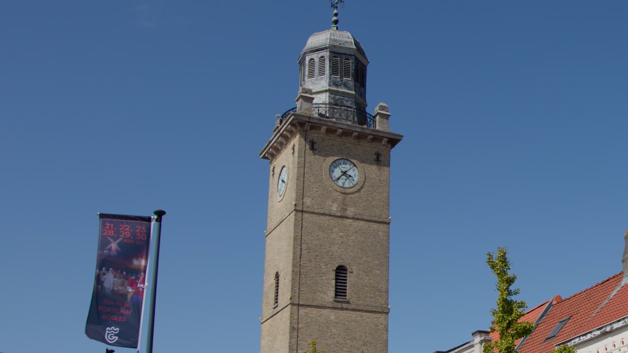 Historic clock tower under clear blue sky, slight camera pan, vibrant summer lighting, Dunkirk, France