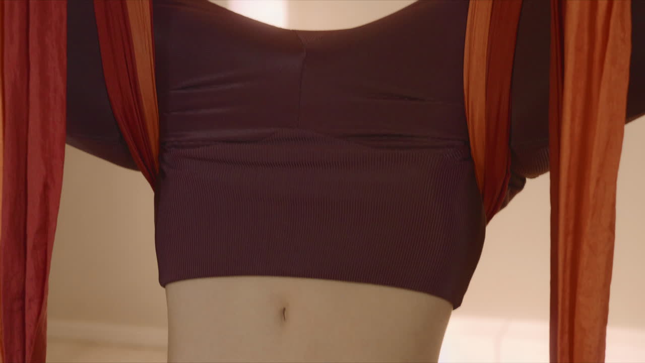 스튜디오에서 거꾸로 된 나비 자세로 명상하는 여성. 비행 요가를 하는 트레이너