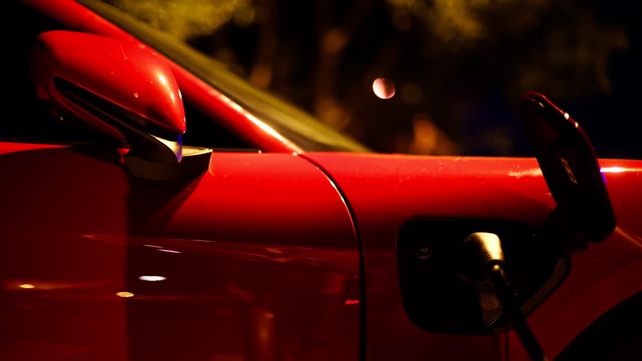 Red, electric car charging on the street at night