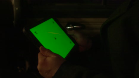 hombre usando una tableta con pantalla verde en un coche por la noche