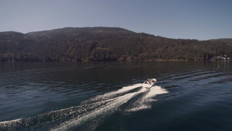 Drone-4K-Footage-of-recreational-speedboats-having-leisure-pastime-during-a-sunny-day-on-a-clam-Cultus-lake-surrounded-by-mountains-ripples-trees-water