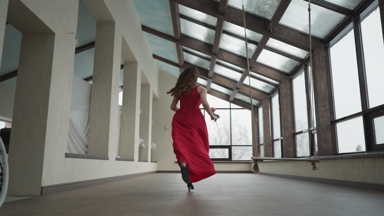Una donna corre verso la vetrina di una galleria d'arte. Una giovane modella in abito scarlatto crea una scena visivamente accattivante vicino alle vetrine della galleria. Movimenti rapidi ed eleganti.