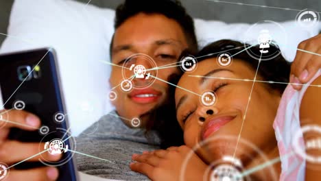 Animation-of-network-of-connections-with-icons-over-biracial-couple-using-smartphone