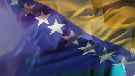 animation of bosnia and herzegovina flag over diverse male and female surgeon performing operation