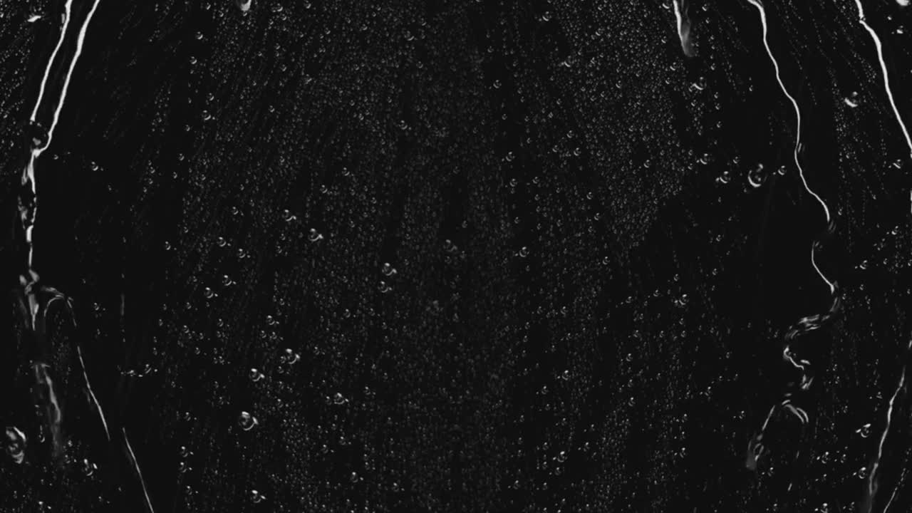 Realistic water drops collect and run down a transparent glass pane on black background, moody weather overlay for dramatic or sad scenes