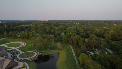 aerial descent down towards a pretty park with a pond in town and country in st