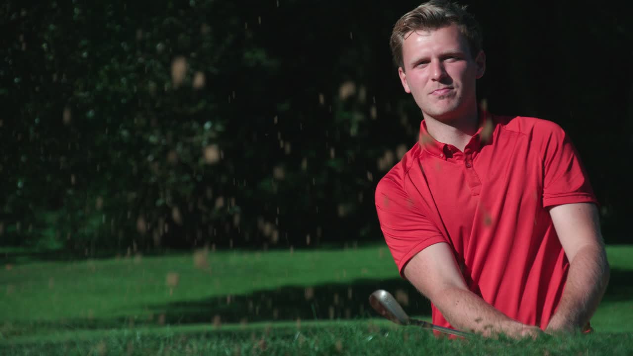 Bir golfçü kum engelinden topu çıkarıyor, golf topunu deliğe sokuyor ve kutluyor.