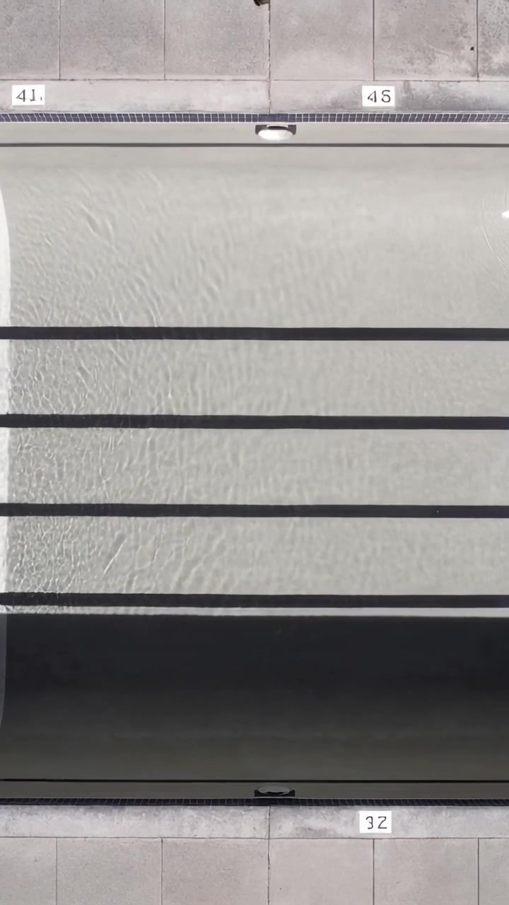 Video verticale: Acqua della piscina increspata dal flusso di filtrazione a bordo piscina, con segnacorsie.