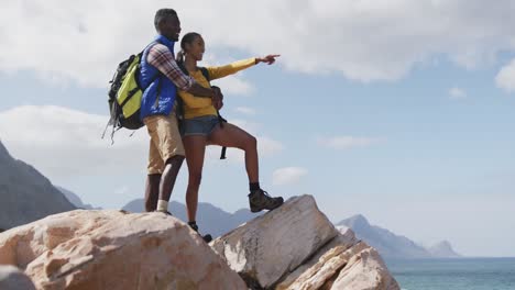 Pareja-Afroamericana-Parada-En-Las-Rocas-Disfrutando-De-La-Vista-Mientras-Hace-Trekking