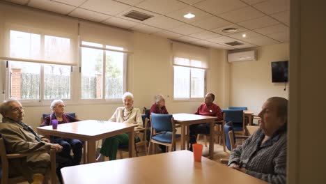 elderly men and women sitting in nursing home canteen