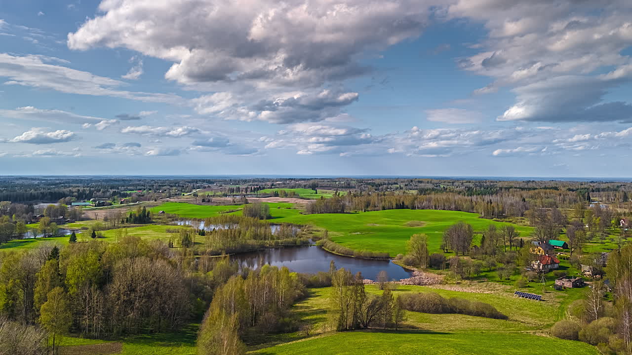 Rural Europe in a picturesque landscape with a pond below a cloudscape aerial time lapse