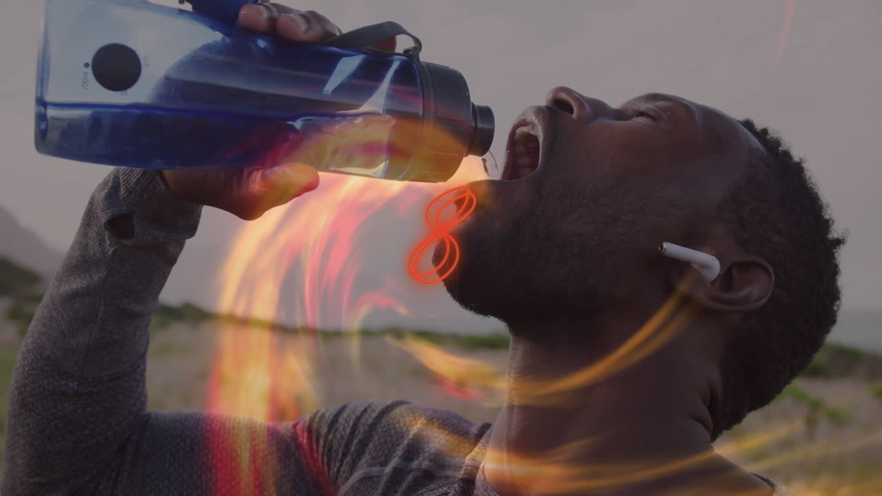 Man pouring water from water bottle while fitness training outdoors with orange flame overlay