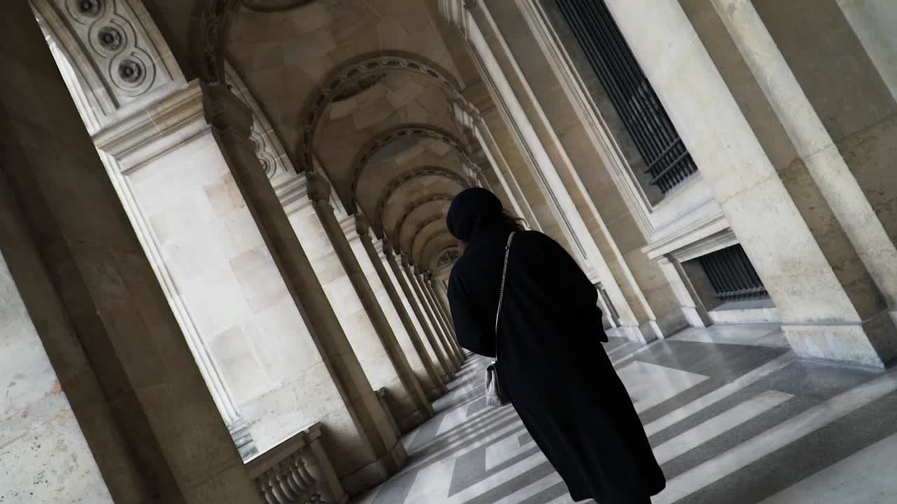 mujer del sur de asia en la pasarela arqueada en el patio interior del museo del louvre en parís francia