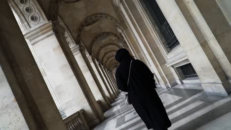 south asian woman on the arched walkway at the inner courtyard of louvre museum in paris france