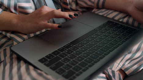 Closeup-girl-using-laptop-browsing-internet-in-pajamas.-Hand-touching-device-pad