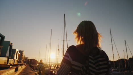 a young woman strolls along the prestigious district of bergen near the pier with yachts the setting