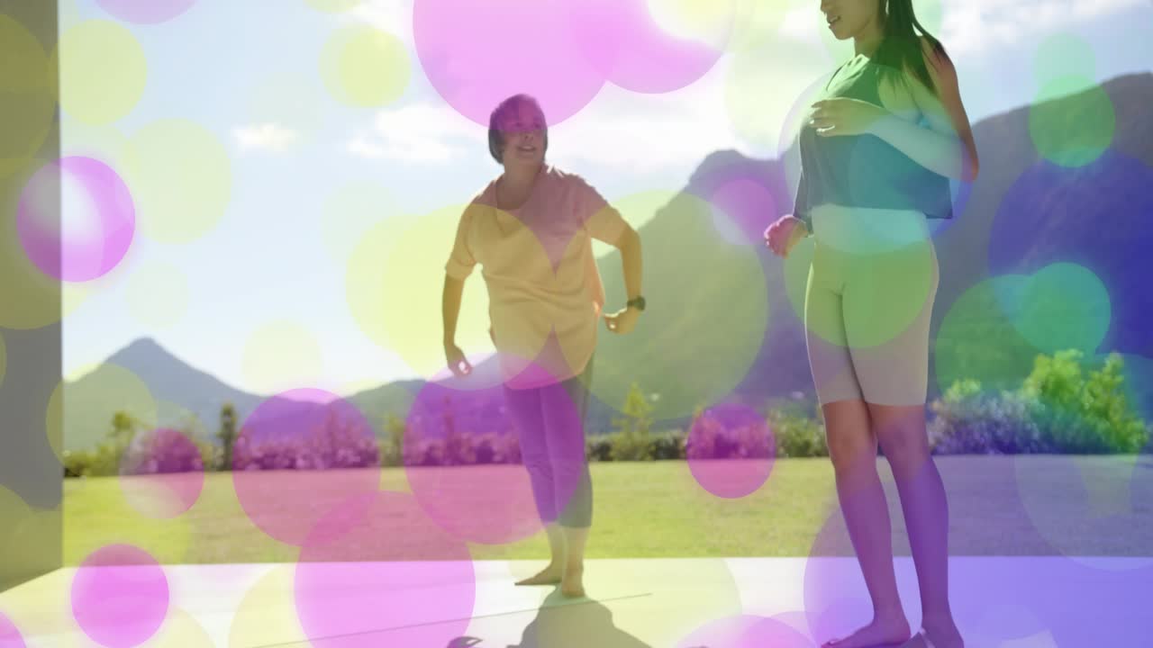 Coach guiding student on yoga mats cueing folding to standing, bokeh showing wristbands for fitness