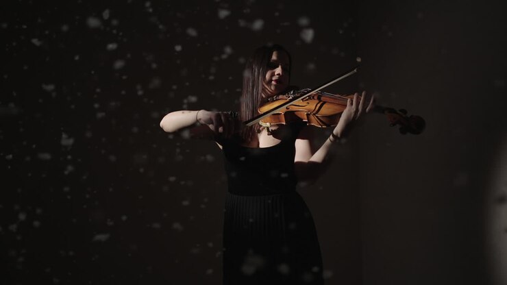 Donna che suona il violoncello in uno studio buio
