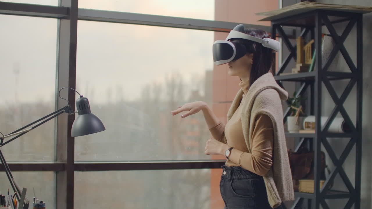 Portrait. Female architect-designer in a virtual reality helmet at in a modern office near a large window with his hands imitates the work of interface. Designing the future the concept of virtual architecture and design interface graphic applications.