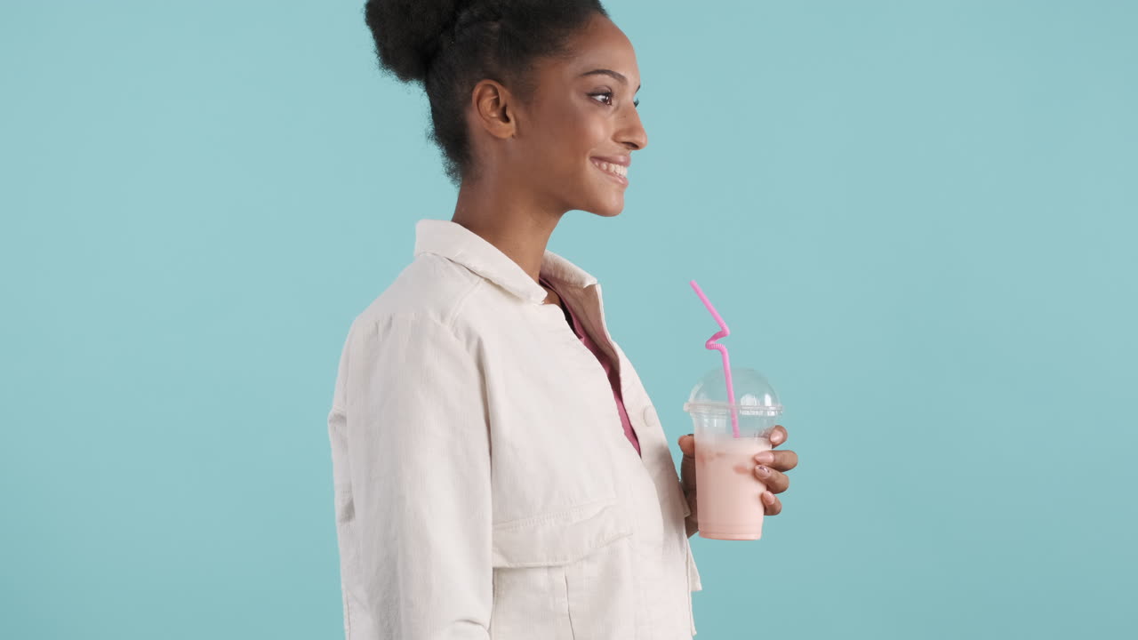 vista lateral de una mujer joven bebiendo un batido