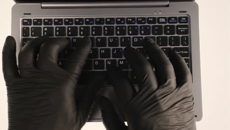 hacker typing on laptop computer black gloves erase the traces hand prints