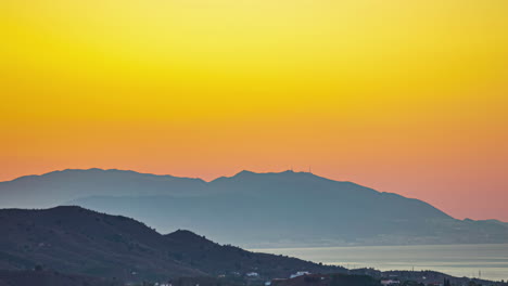 golden sunrise over mountainous landscape with hazy sky and silhouette of hills