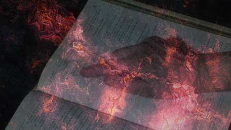 hand reaching over open book with fiery abstract animation overlay