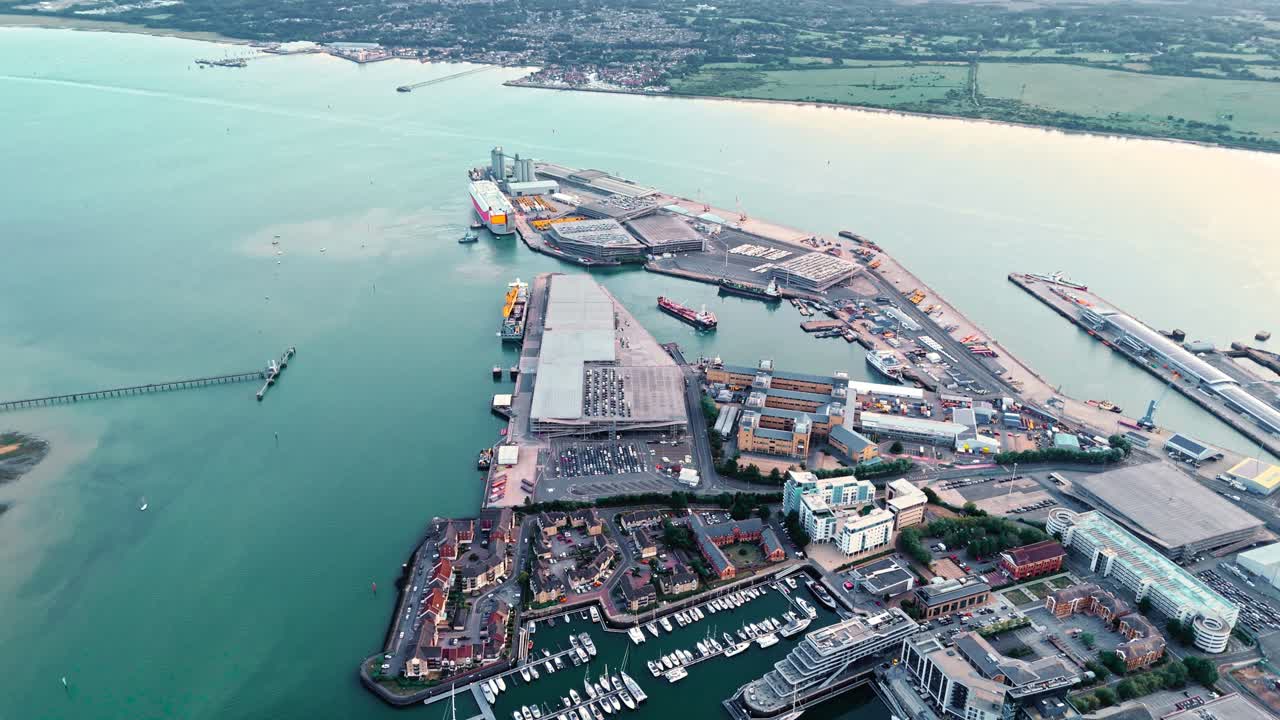 High-angle aerial drone view of Southampton port dock, featuring boats, cargo ships, and calm sea waters illuminated by warm autumn sunset light across the busy maritime scene