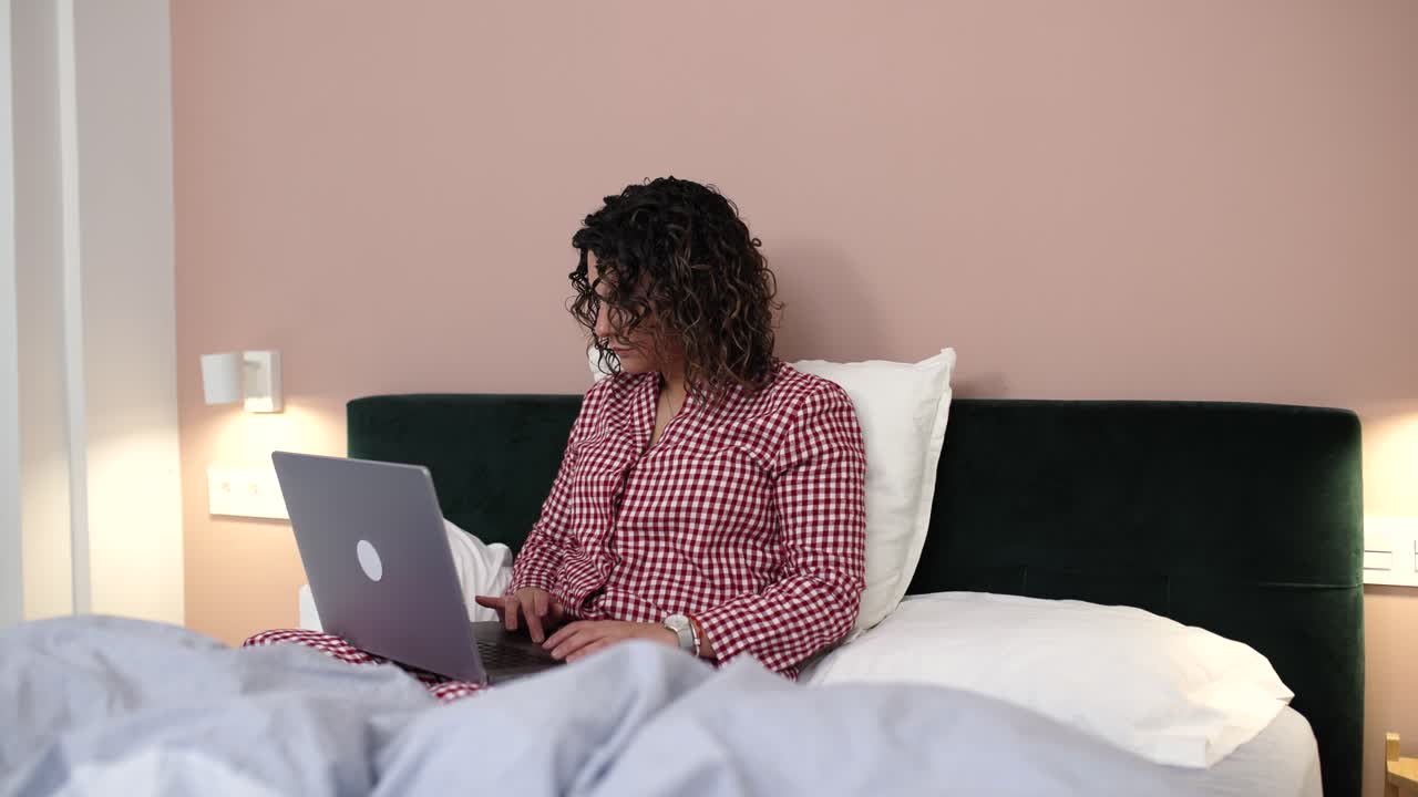 Woman working from home in bed on laptop