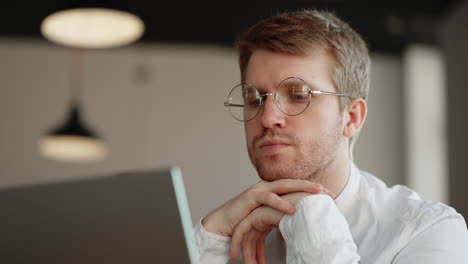 pensive-businessman-is-thinking-and-answering-in-online-chat-in-laptop-closeup-portrait
