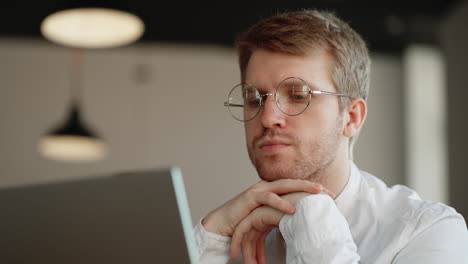 pensive businessman is thinking and answering in online chat in laptop closeup portrait