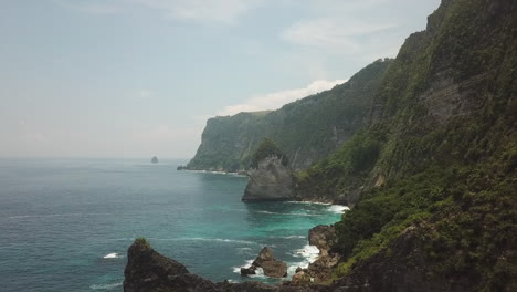 steep misty jungle rock cliffs drop to calm