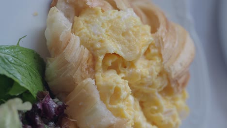 croissant with scrambled eggs and salad