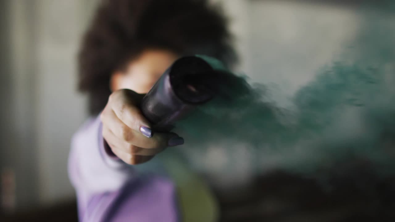 Woman pointing launcher at camera, emitting green smoke and forming emoji stream for social media