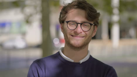 hombre alegre con gafas mirando a la cámara al aire libre