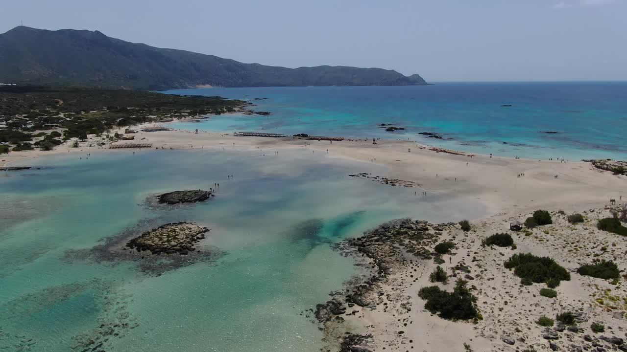 Calm saltwater lagoon at Elafonissi Beach in Crete Greece with rocky reefs, Aerial dolly out shot