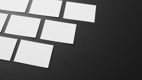 Close-up-of-white-business-cards-arranged-on-black-background,-copy-space,-slow-motion