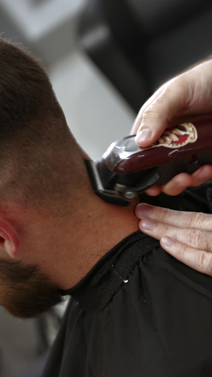 Nærbillede af en barber, der bruger klippemaskiner til en klipning