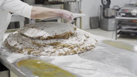 slow motion panning shot of a pastry chef portioning and processing a mass or dough for sweets with a metal tablet