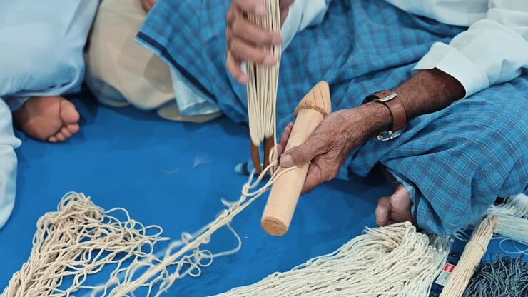 An Arab fisherman is weaving a fishing net in an old, traditional way