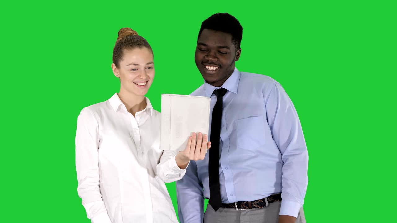 Giovane donna d'affari caucasica e la sua collega africana che fanno una videochiamata con un tablet su schermo verde, Chroma Key