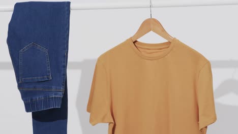 video of denim trousers and yellow t shirt on hanger and copy space on white background