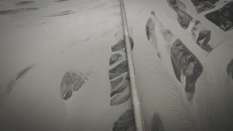 Aerial-bridge-leading-over-glacial-river-bed-in-iceland-landscape-view