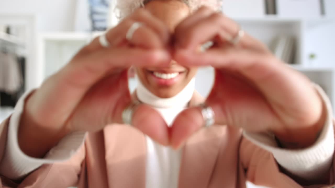 Happy african american woman smiling tenderly demonstrating heartshaped hands