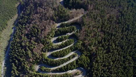 Slow-flyover-of-semi-trucks-traveling-winding-road-over-Bratocea-Pass,-Romania