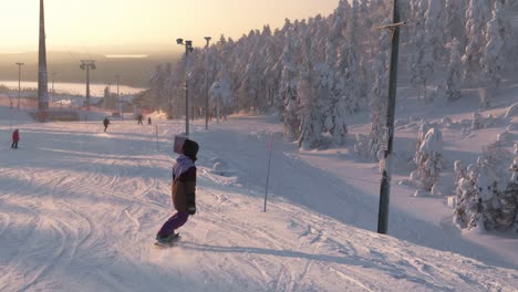 Siguiendo-A-La-Dama-Haciendo-Snowboard-Cuesta-Abajo-En-Una-Pista-De-Esquí-Al-Atardecer